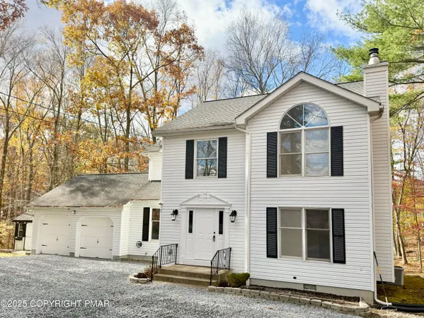 a view of a white house with large windows next to a road