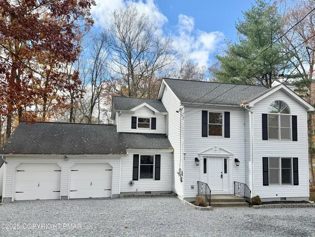 a view of a white house with a yard and garage