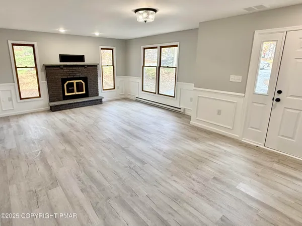 an empty room with windows and fireplace