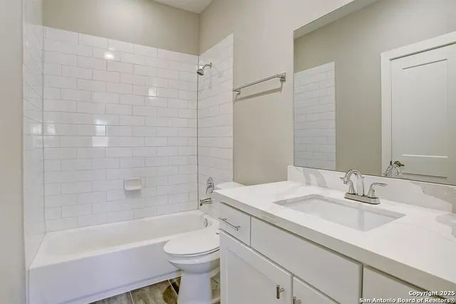 a bathroom with a bathtub shower sink vanity mirror and toilet