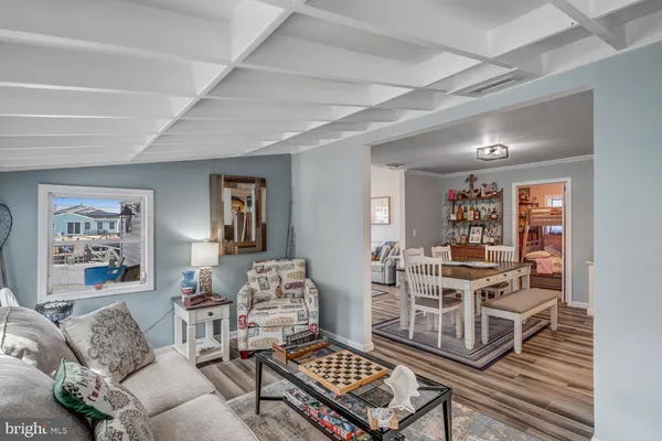 a living room with stainless steel appliances furniture a rug and a bookshelf