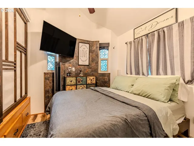 a bedroom with a bed television with the wooden floor