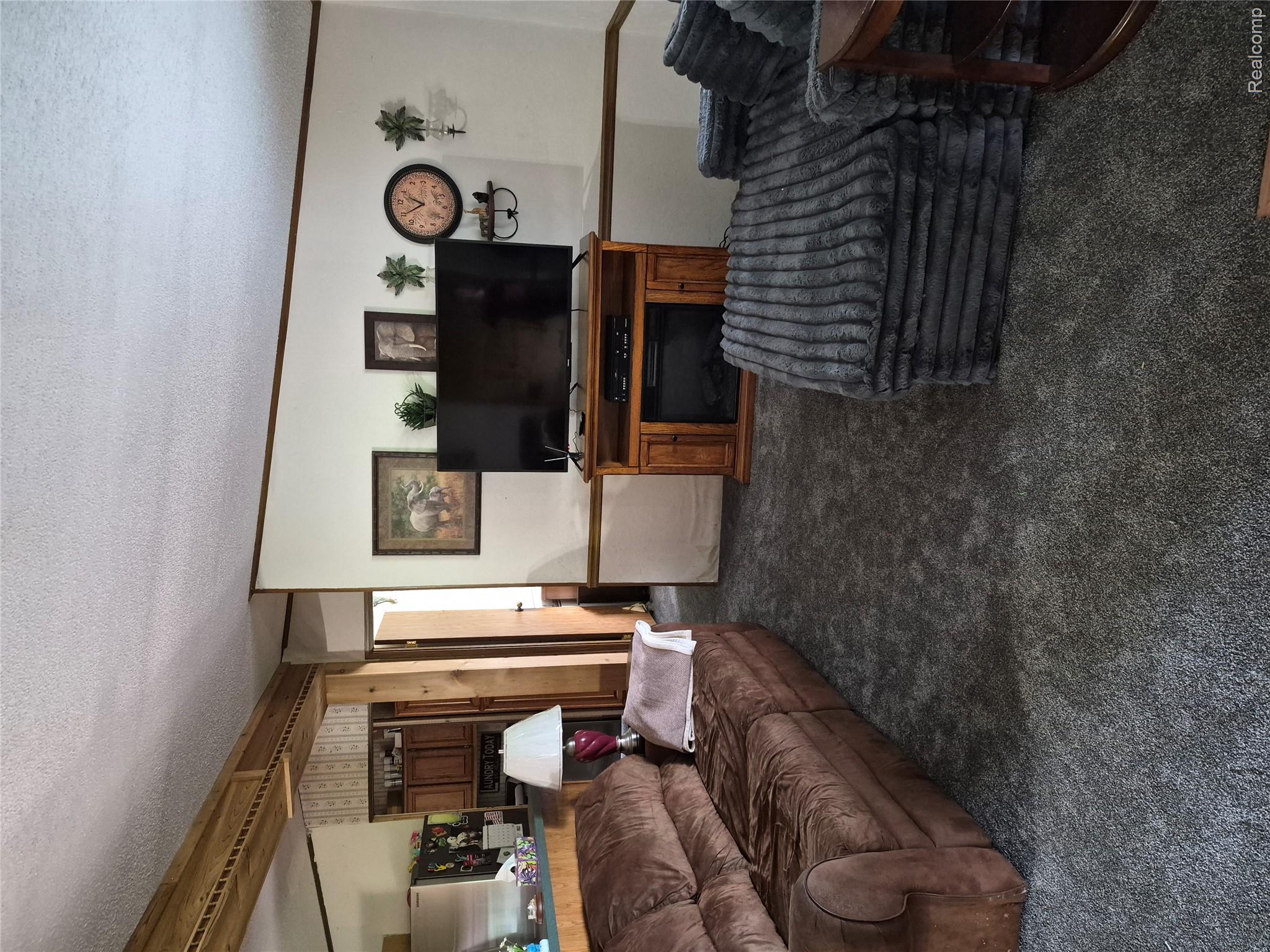 12849 South Delaney Road Perry, MI 48872 - Photo 21 of 34 Spacious room featuring gray carpeting, an entertainment center with an electric fireplace, and a vaulted ceiling