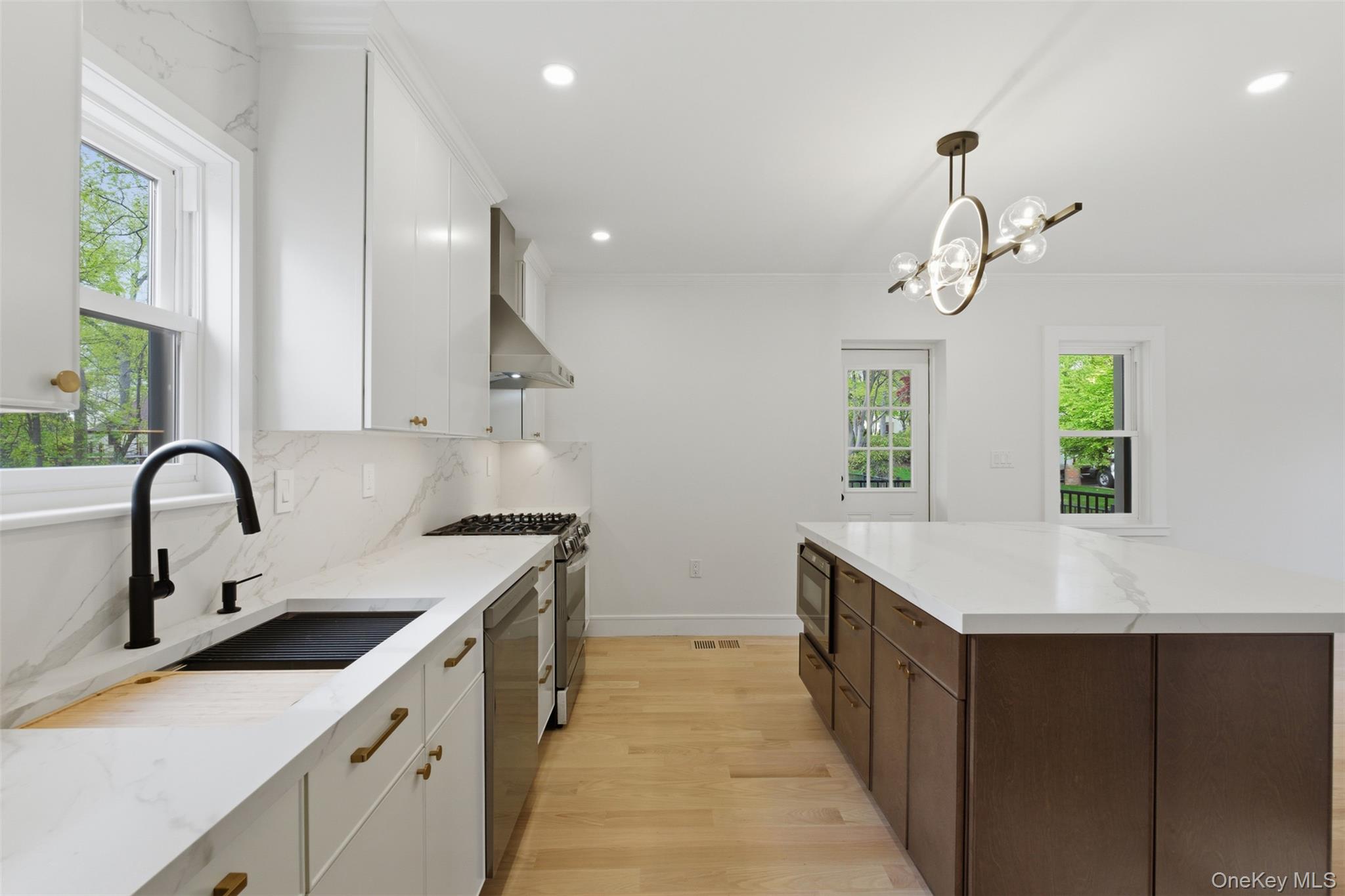 40 Calhoun Avenue New Rochelle, NY 10801 - Photo 8 of 49 Open-concept kitchen featuring an expansive center island with imported Italian porcelain countertops, built-in microwave, white shaker cabinetry, stainless steel appliances, and a sleek matte black faucet.