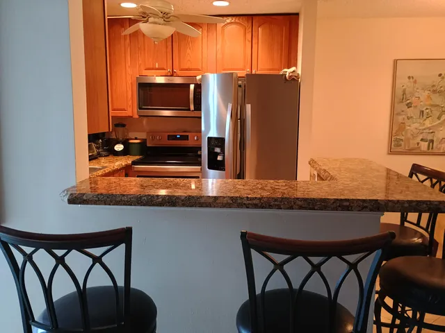 a kitchen with stainless steel appliances granite countertop a table chairs and a refrigerator