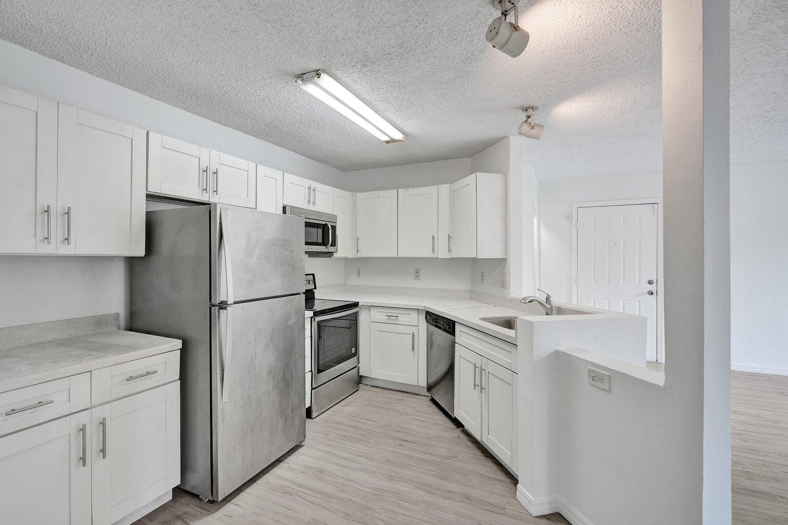 a kitchen with cabinets appliances and wooden floor