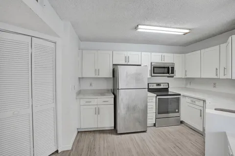 a kitchen with cabinets stainless steel appliances and wooden floor