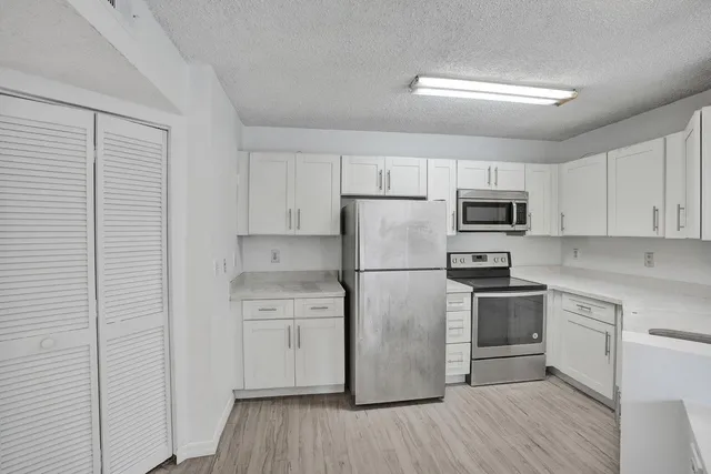 a kitchen with cabinets stainless steel appliances and wooden floor