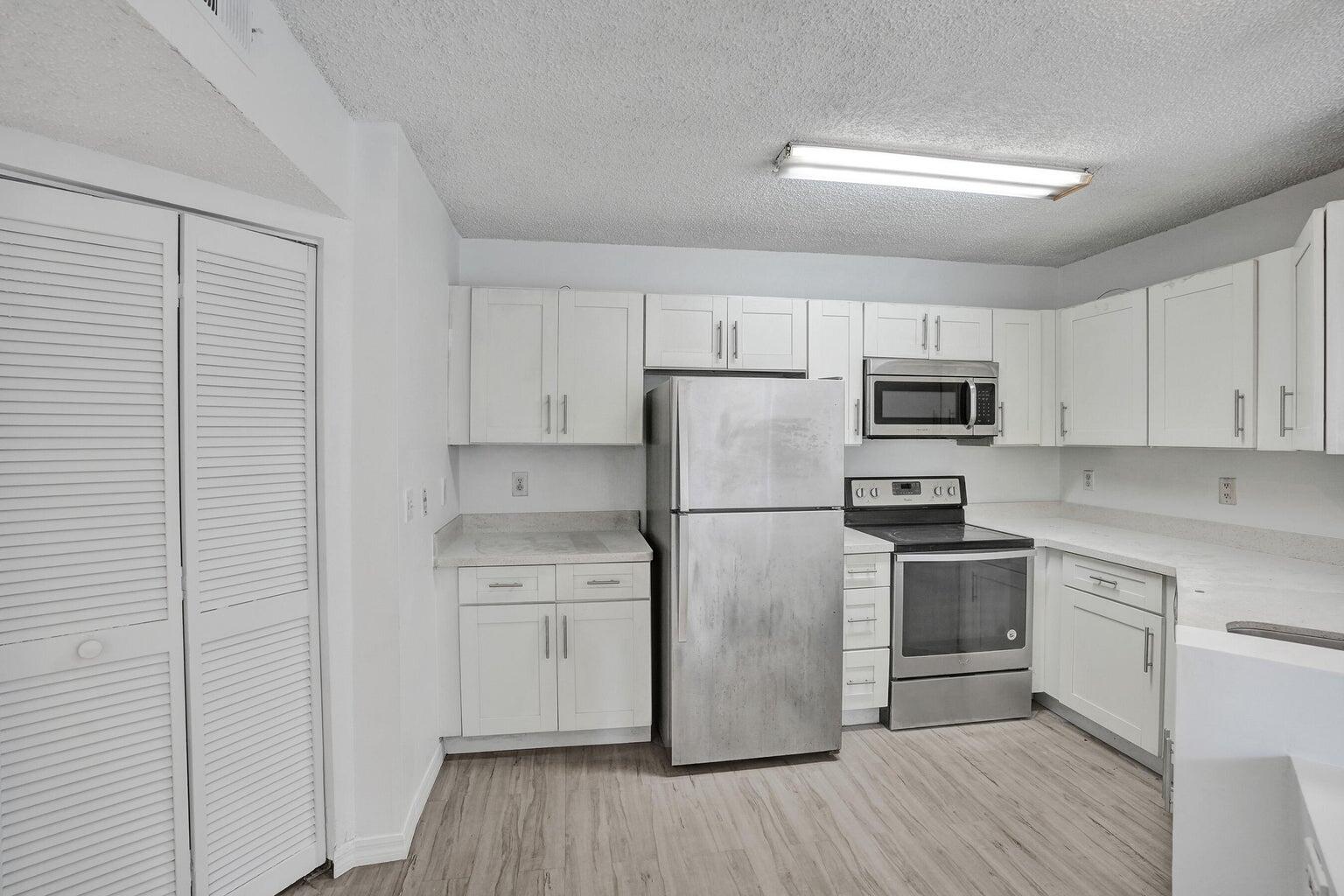 4015 West McNab Road, Unit D204 Pompano Beach, FL 33069 - Photo 12 of 46 a kitchen with cabinets stainless steel appliances and wooden floor