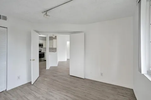 a view of empty room with wooden floor and window