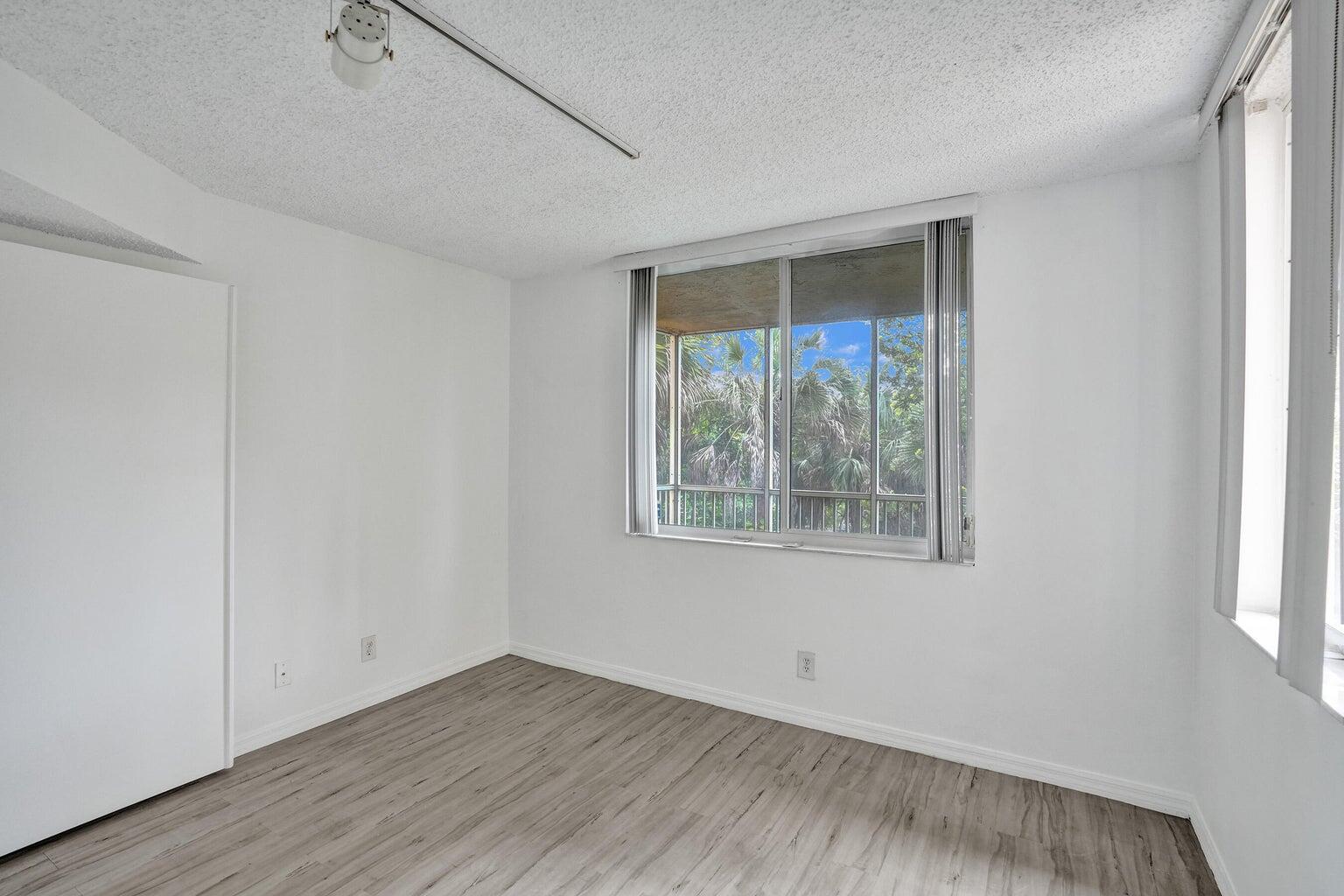 4015 West McNab Road, Unit D204 Pompano Beach, FL 33069 - Photo 22 of 46 a view of an empty room with wooden floor and a window