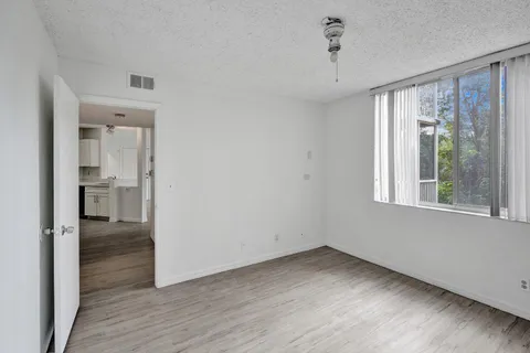 a view of empty room with wooden floor and fan