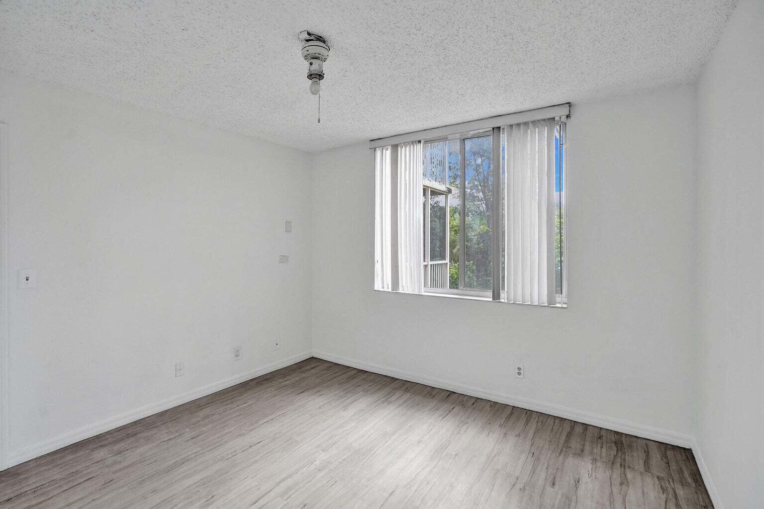 4015 West McNab Road, Unit D204 Pompano Beach, FL 33069 - Photo 32 of 46 a view of an empty room with wooden floor and a window