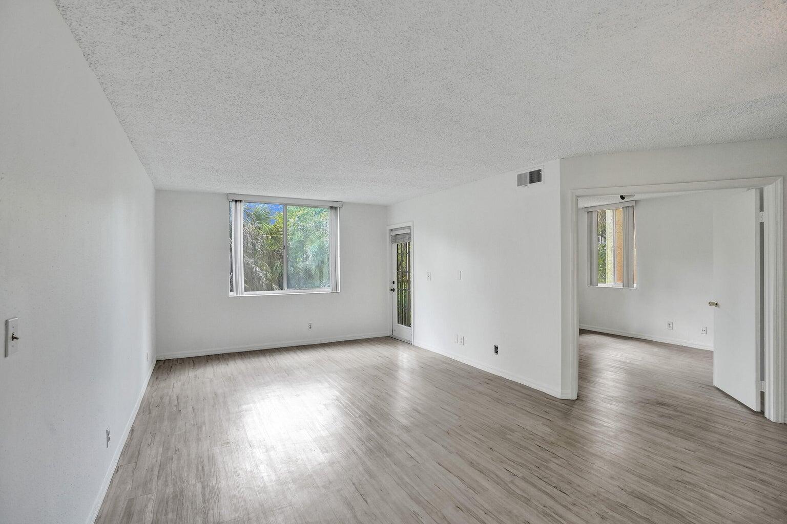 4015 West McNab Road, Unit D204 Pompano Beach, FL 33069 - Photo 6 of 46 an empty room with wooden floor and windows