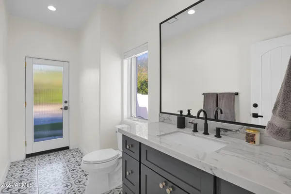 a bathroom with a granite countertop sink mirror vanity and toilet