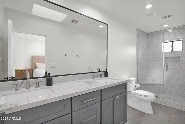 a bathroom with a double vanity sink toilet and a mirror