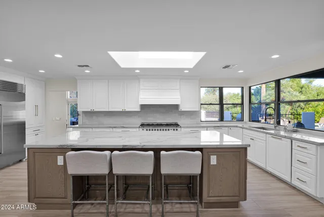 a kitchen with kitchen island granite countertop a table chairs sink and cabinets