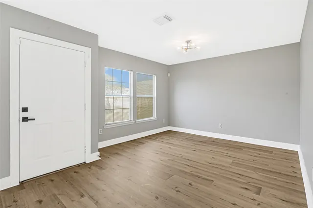 a view of an empty room with wooden floor and a window