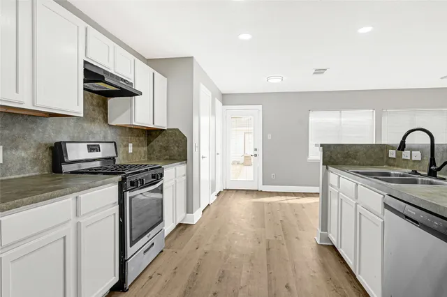 a kitchen with granite countertop wooden floors a stove and a sink