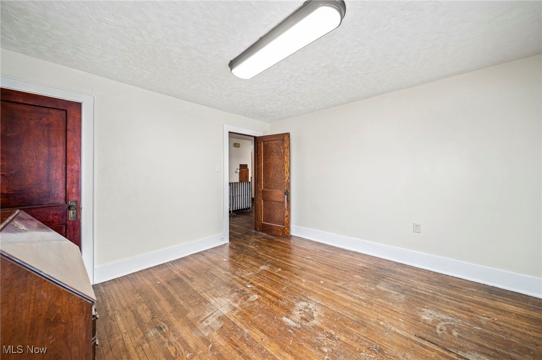 977 West Prospect Road Ashtabula, OH 44004 - Photo 27 of 42 Unfurnished room featuring dark wood-style floors, a textured ceiling, and radiator heating unit