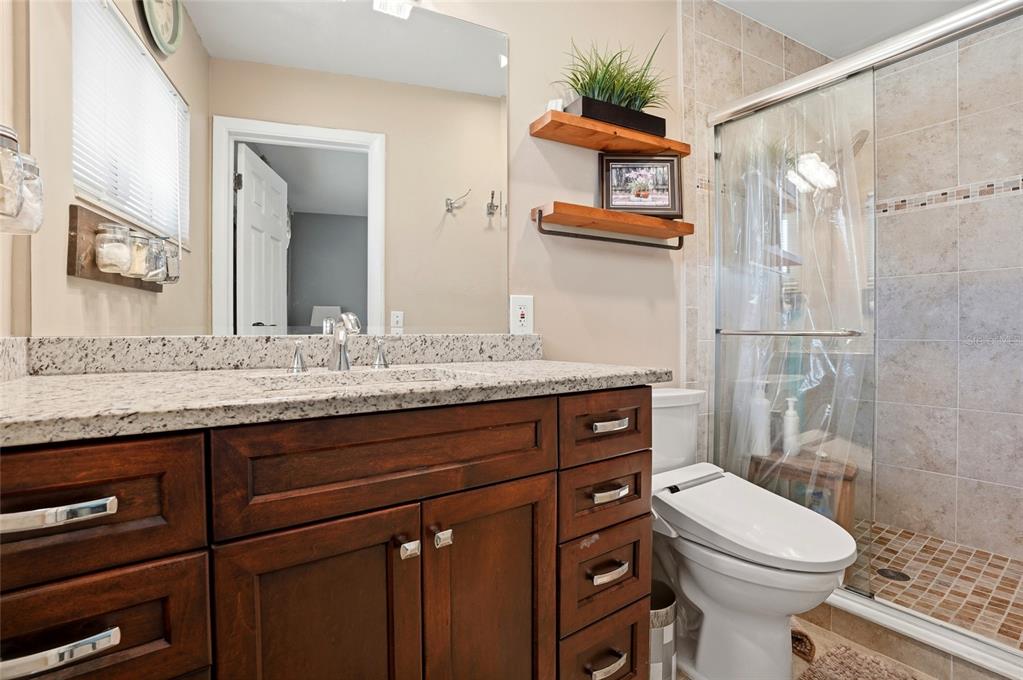 6641 12th Avenue North St. Petersburg, FL 33710 - Photo 4 of 18 a bathroom with a granite countertop toilet sink and mirror