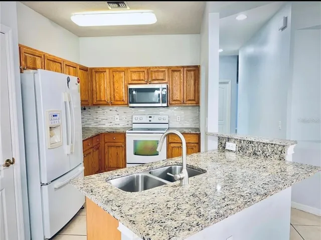 a kitchen with stainless steel appliances granite countertop a sink refrigerator and cabinets