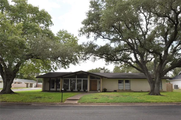 a front view of a house with a garden and trees