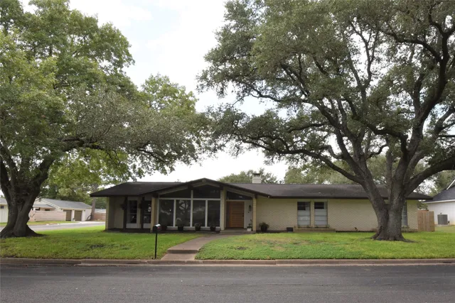 a front view of a house with a garden and trees