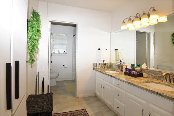 a bathroom with a double vanity sink a toilet and a mirror