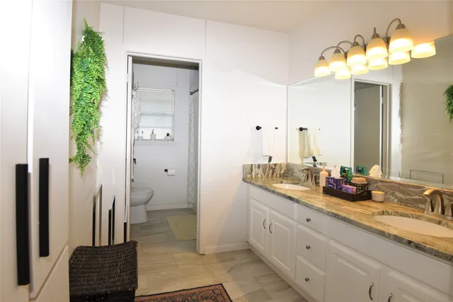 a bathroom with a double vanity sink a toilet and a mirror