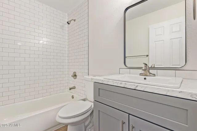 a bathroom with a granite countertop toilet a sink a mirror a bathtub and shower