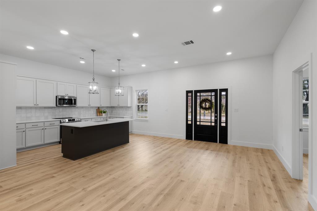 a large kitchen with a large counter top a sink stainless steel appliances and cabinets