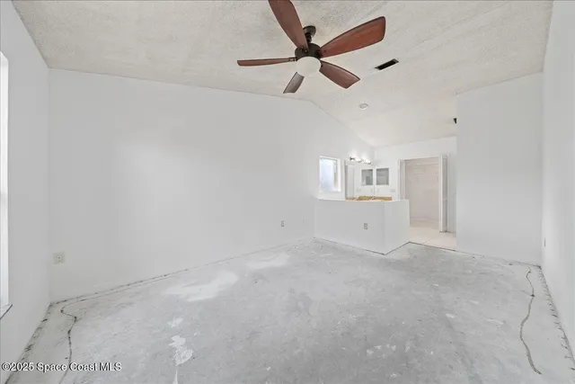 en empty room with ceiling fan and windows