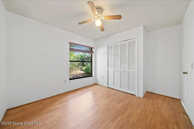 a view of an empty room with window and wooden floor