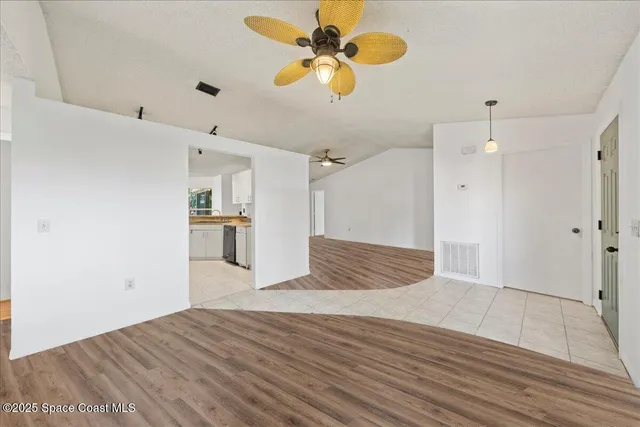 a view of empty room with wooden floor and ceiling fan