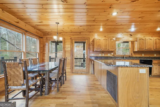 a kitchen with stainless steel appliances kitchen island granite countertop a table chairs and a chandelier