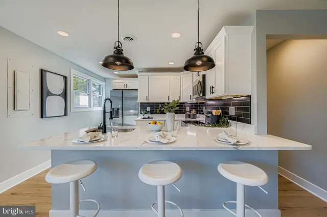 a kitchen with stainless steel appliances granite countertop a sink a stove a dining table and chairs with wooden floor