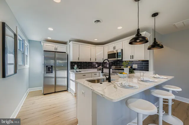 a kitchen with stainless steel appliances kitchen island granite countertop a sink a stove a refrigerator and island with wooden floor