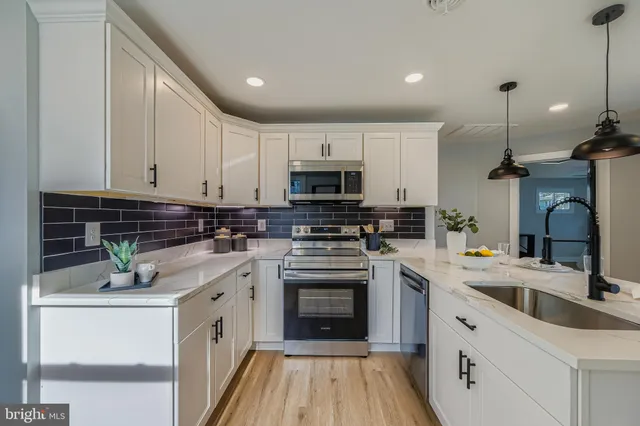 a kitchen with granite countertop a sink stainless steel appliances and white cabinets