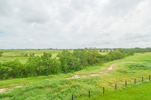 a view of a green field with wooden fence