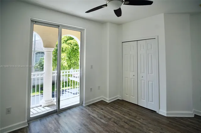 an empty room with wooden floor fan and windows