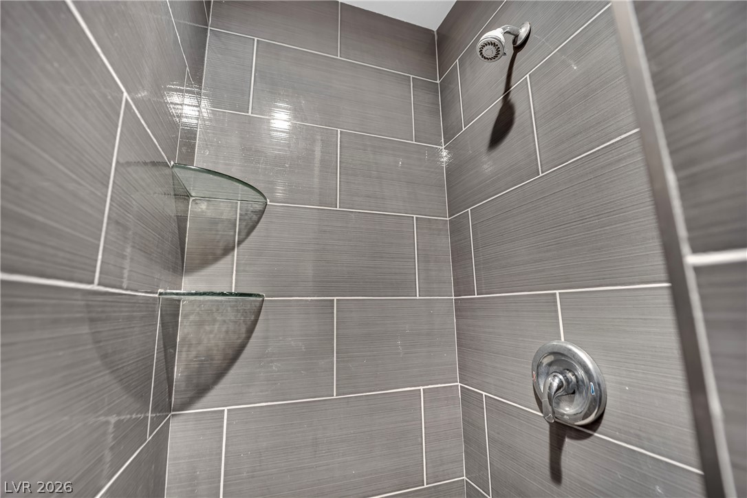 420 North Racetrack Road Henderson, NV 89015 - Photo 29 of 52 A well-lit shower features contemporary gray tile and practical glass shelving.