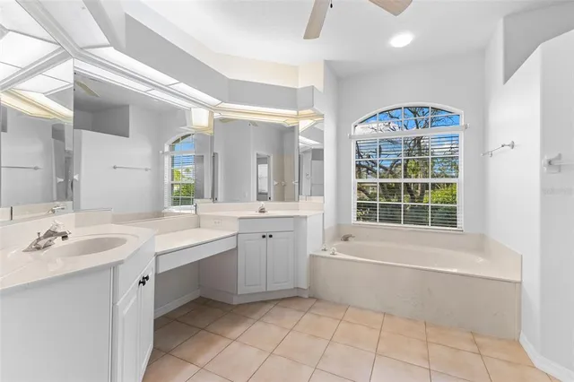 a bathroom with a bathtub a double vanity sink a vanity a window and a mirror