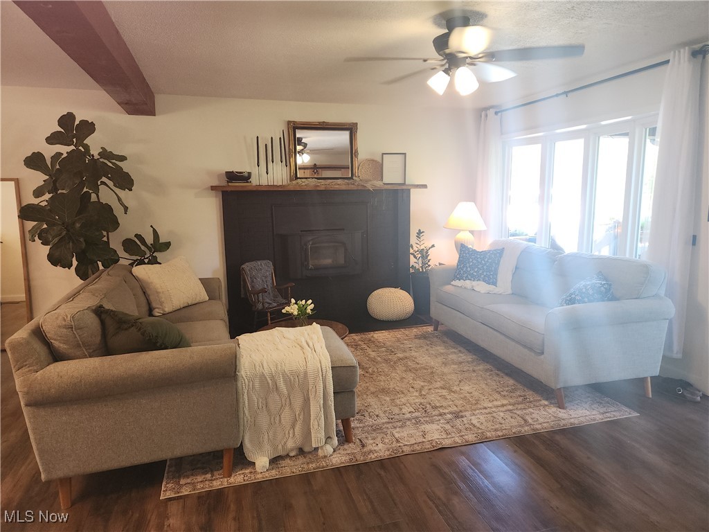755 Maple Brook Road New Concord, OH 43762 - Photo 4 of 12 Living room featuring beamed ceiling, ceiling fan, a wood stove, and dark hardwood / wood-style flooring
