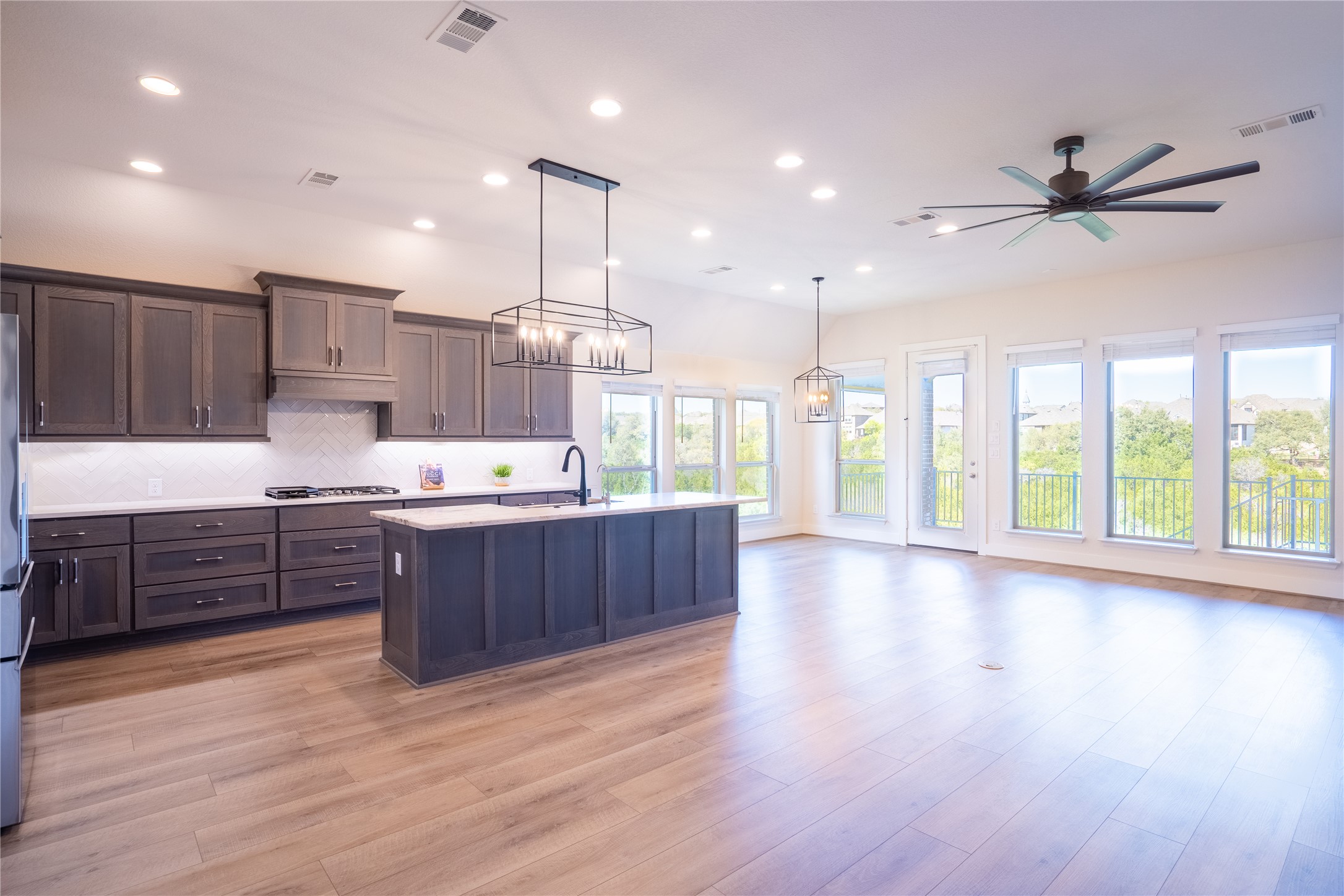 1309 Spring Gulch Lane Georgetown, TX 78628 - Photo 27 of 27 Kitchen featuring pendant lighting, a kitchen island with sink, open floor plan, light wood-type flooring, and tasteful backsplash