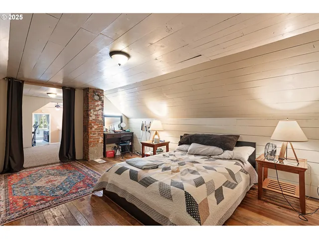 a bedroom with a bed a mirror and a flat tv screen on dresser