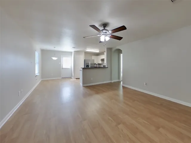 a view of a big room with wooden floor a ceiling fan and windows