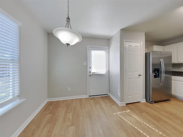 a view of an empty room with window and wooden floor