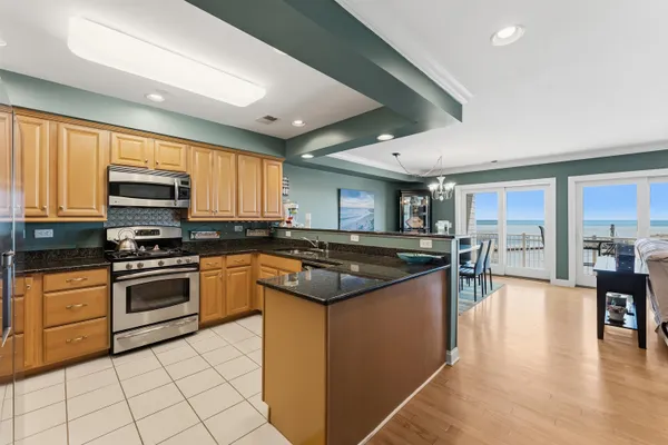a kitchen with stainless steel appliances granite countertop a stove top oven a sink dishwasher a dining table and chairs with wooden floor