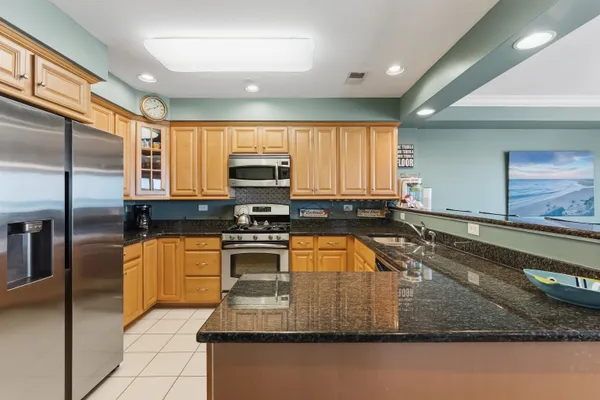 a kitchen with stainless steel appliances granite countertop a sink a stove counter space and a refrigerator